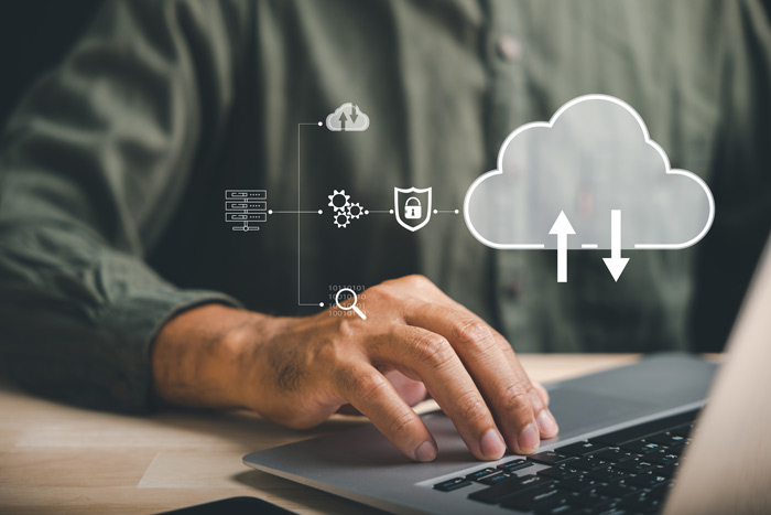 A man working on a computer with a cloud icon over the top