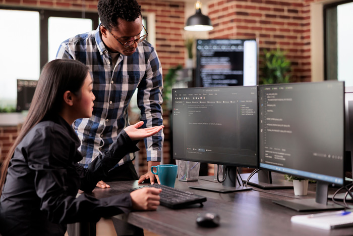 Man and a woman looking at code on a computer